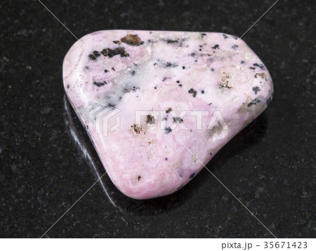 tumbled rhodochrosite gem on dark background 35671423