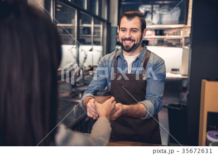 Outgoing barista offering mug to client Outgoing barista offering mug to client 35672631