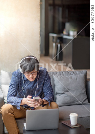 Young Asian man listening to music on sofa 35677963