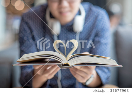 Young man holding book, heart shape page folded 35677968