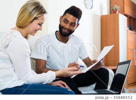 Interracial couple discussing banking offer for mortgage at home 35686552