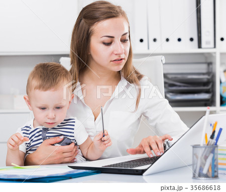Mother with kid is working behind laptop Mother with kid is working behind laptop 35686618