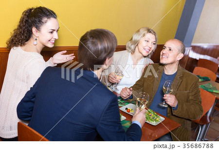 Four adults with wine and dinner laughing in restaurant 35686788