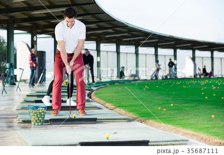 Man playing golf is going to hit ball at golf course Man playing golf is going to hit ball at golf course 35687111