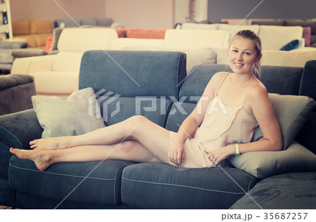 Young female customer barefoot choosing sofa Young female customer barefoot choosing sofa 35687257