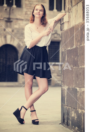 Positive young girl standing near the stone wall 35688053