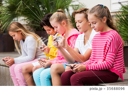 Five kidsare chatting on their smartphone Five kidsare chatting on their smartphone 35688096