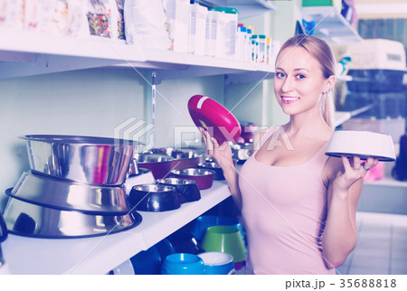 Girl looking for pet bowls in pet shop Girl looking for pet bowls in pet shop 35688818