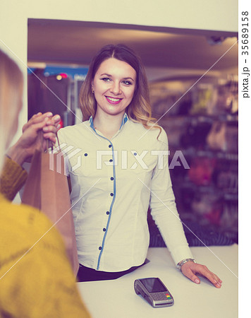 Woman seller is handing numerous purchases to client Woman seller is handing numerous purchases to client 35689158