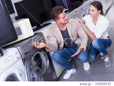 Smiling family couple selecting new clothes washer Smiling family couple selecting new clothes washer 35689542