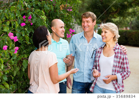 Portrait of mature cheerful males and females talking outdoors Portrait of mature cheerful males and females talking outdoors 35689834