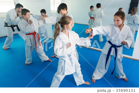 Glad kids sparring in pairs in karate class 35690131