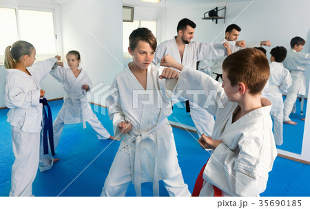 Teenagers practicing new karate moves in pairs in class 35690185