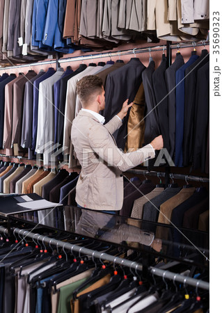 attractive male customer examining men’s suits 35690323