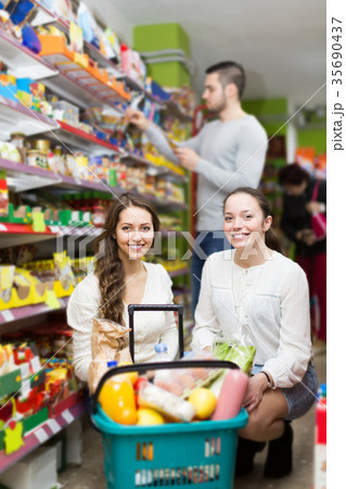 customers standing near shelves with canned goods at shop 35690437