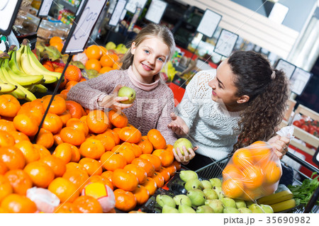 Woman and little girl buying fruits. 35690982
