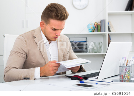 Frustrated manager doing paperwork at office. 35691014
