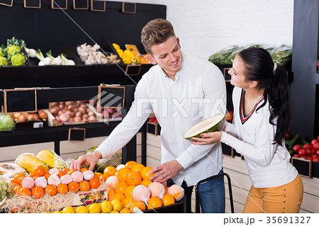 Ordinary couple deciding on fruits in shop Ordinary couple deciding on fruits in shop 35691327