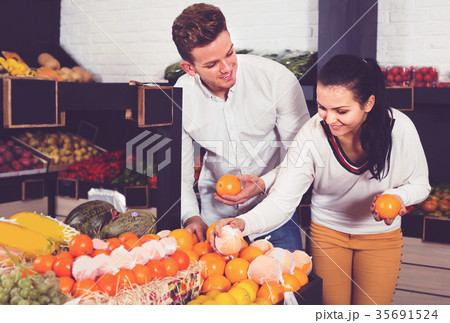 Smiling couple examining various fruits 35691524