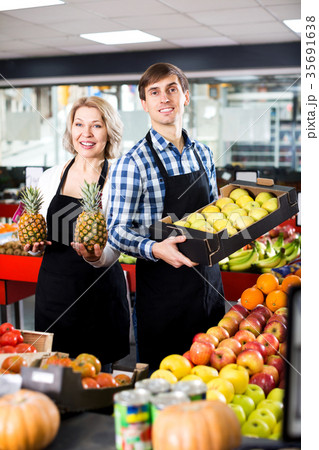 Senior woman and young man offering seasonal fruits 35691638