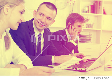 Laughing coworkers working and talking on phone 35691782