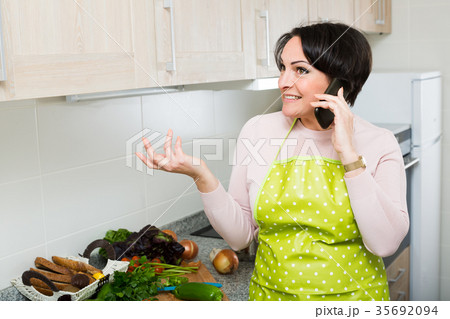 Housewife with phone at kitchen . Housewife with phone at kitchen . 35692094
