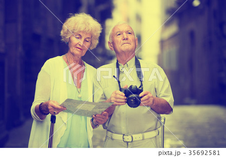 Senior woman and man traveling together looking for destination with city map Senior woman and man traveling together looking for destination with city map 35692581