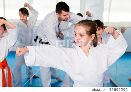 Young trainer is correcting children moves Young trainer is correcting children moves 35692596