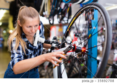 Portrait of girl who is working with pliers and fixing wheels in workshop. Portrait of girl who is working with pliers and fixing wheels in workshop. 35692708