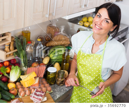 Cheerful woman is posing in time cooking on the kitchen Cheerful woman is posing in time cooking on the kitchen 35692770