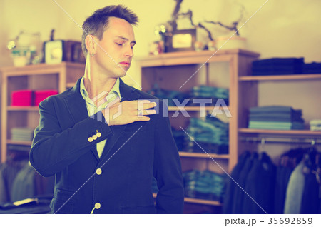 Male customer is trying on new dark blue jacket Male customer is trying on new dark blue jacket 35692859