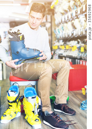 Customer man is trying on new boots for skiing 35692968