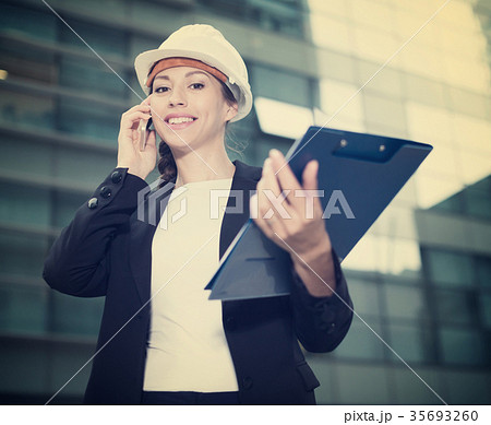 Woman architector in suit and hat is talking about project by the phone Woman architector in suit and hat is talking about project by the phone 35693260