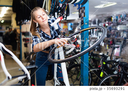 Female is fixing wheels of bicycle in workshop. Female is fixing wheels of bicycle in workshop. 35693291