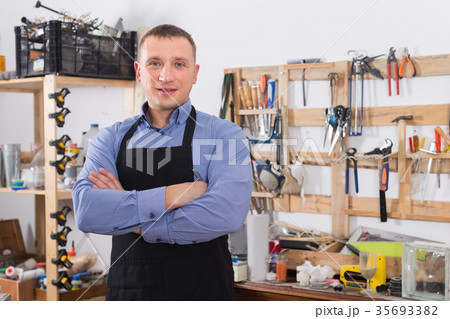 Portrait of positive adult handsome woodworker in workwear in garage Portrait of positive adult handsome woodworker in workwear in garage 35693382