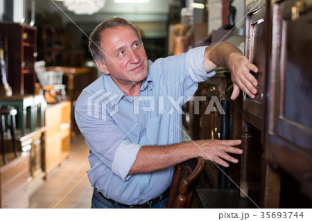 Mature man is shopping the old cupboard 35693744