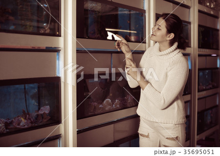 Girl in aquarium shop points to colored fish 35695051