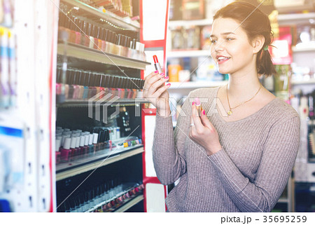 Smiling woman customer browsing rows of lipstick 35695259