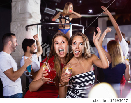 smiling women dancing in the night club with drinks in the hand smiling women dancing in the night club with drinks in the hand 35695637