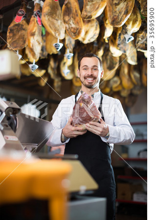 cheerful male shop assistant using scales for meat in butcher’s shop cheerful male shop assistant using scales for meat in butcher’s shop 35695900