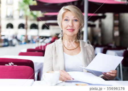 Mature woman is lunching and reading documents Mature woman is lunching and reading documents 35696176