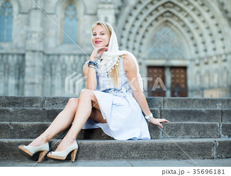 smiling woman sitting in the city center in shawl smiling woman sitting in the city center in shawl 35696181