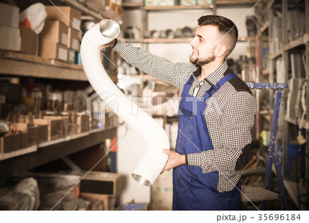 worker choosing flexible aluminum pipe for ventilation in workshop 35696184