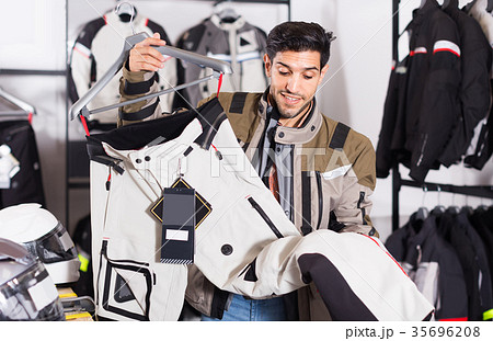 man is choosing new pants for motorbike in the moto store. 35696208