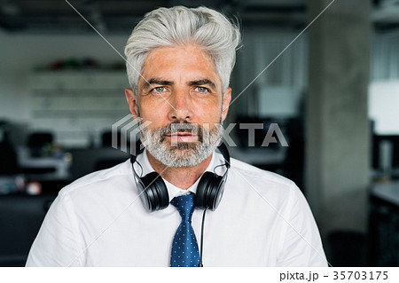 Mature businessman with headphones in the office. Mature businessman with headphones in the office. 35703175