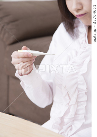 熱を計る若い女性 風邪 インフルエンザ 体温計 ボディパーツ パーツカット 顔なしの写真素材