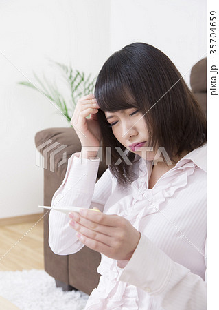 熱を計る若い女性 風邪 インフルエンザ 体温計の写真素材