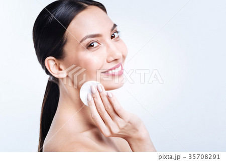 Cheerful woman removing foundation from her face Cheerful woman removing foundation from her face 35708291