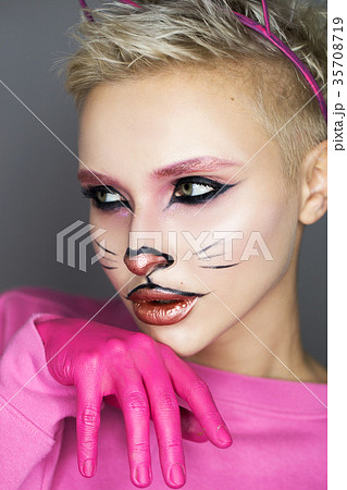 Blonde with cat face. In a pink sweater. On a gray Blonde with cat face. In a pink sweater. On a gray 35708719