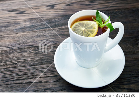Tea with lemon in white cup, cinnamon sticks Tea with lemon in white cup, cinnamon sticks 35711330